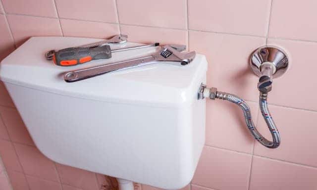 A toilet tank with some tools on top of it