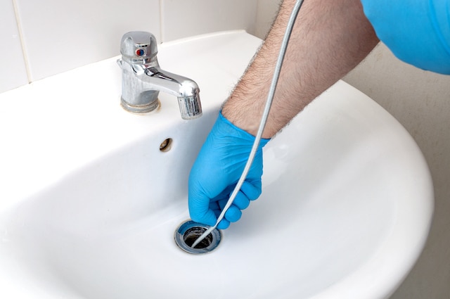 A plumber using a drain snake