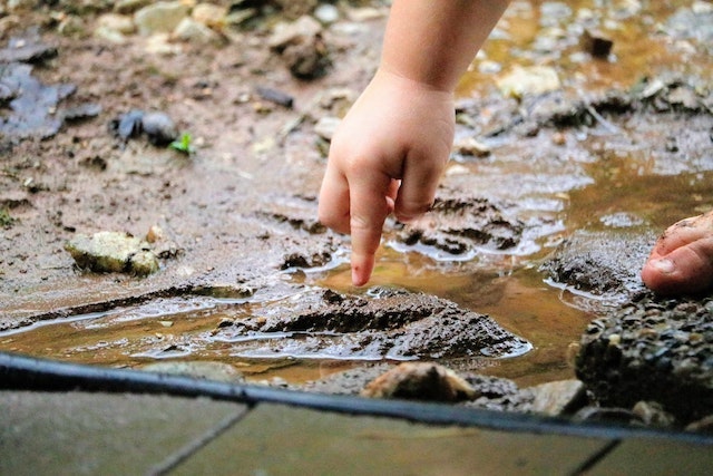 A child pointing to a puddle