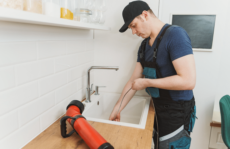 A plumber using a drain snake 