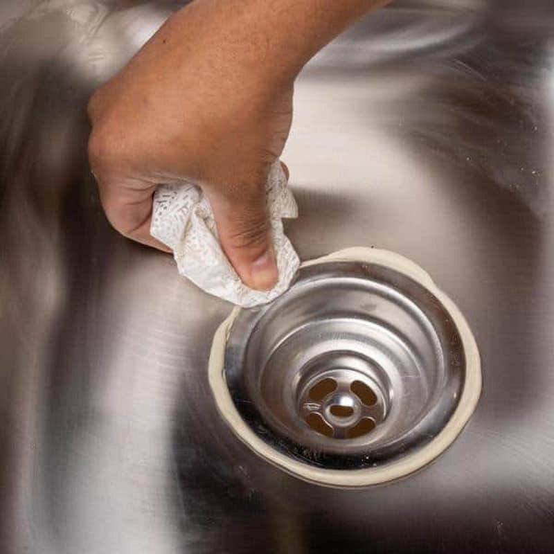 A plumber applying plumbers putty 