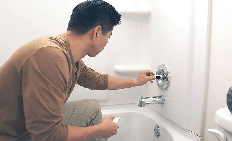 A home owner fixing their tub faucet 