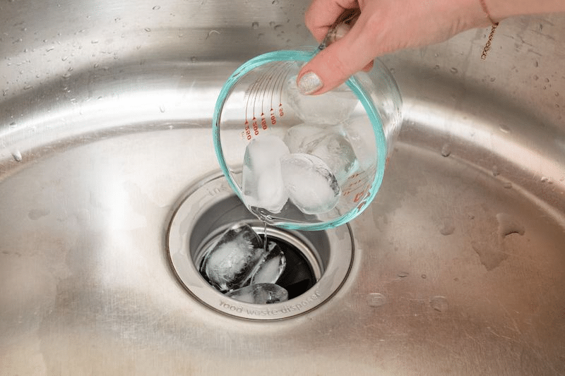 Ice blocks being poured down a garbage disposal 