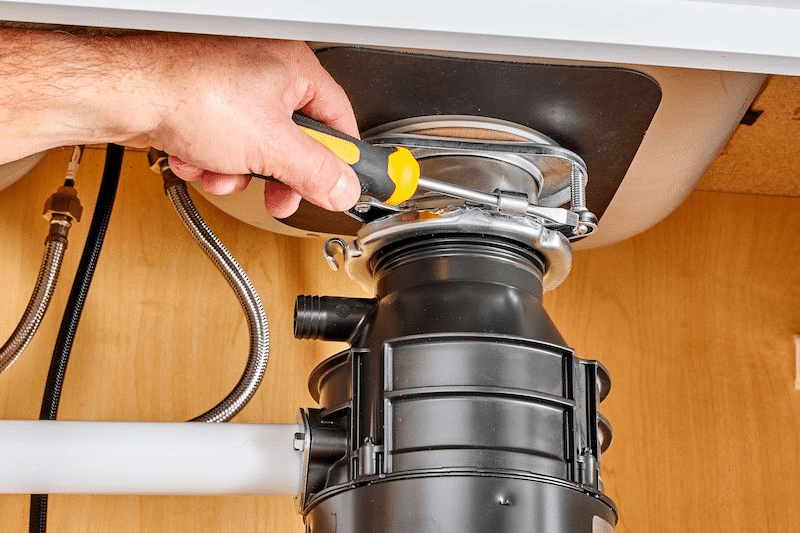 A plumber fixing a garbage disposal 