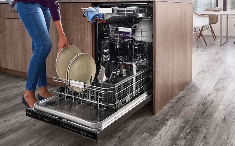 A woman using her dishwasher 
