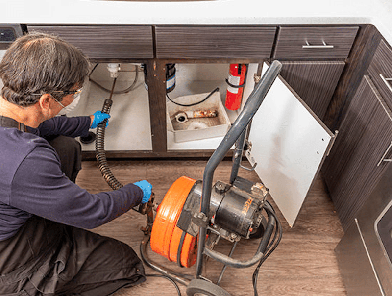 A plumber using a drain auger