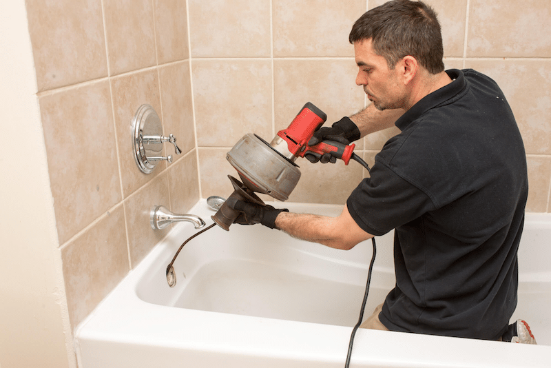 A plumber using a drain auger 