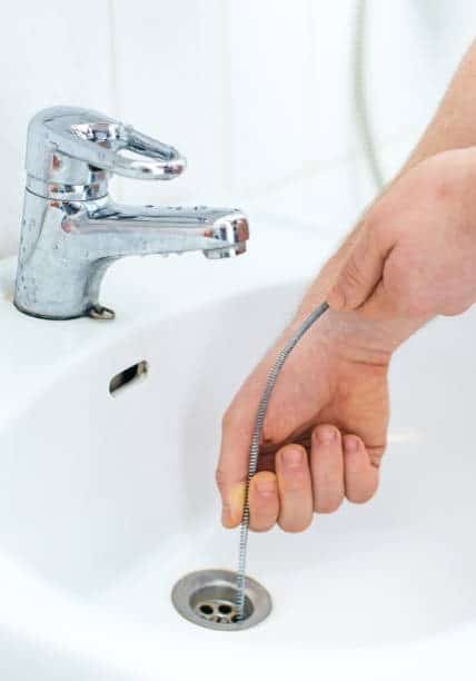 A homeowner using a sewer snake 