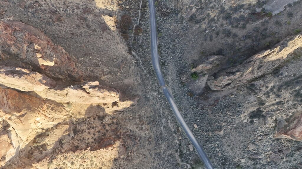 Aerial view of a narrow road through rocky desert terrain.