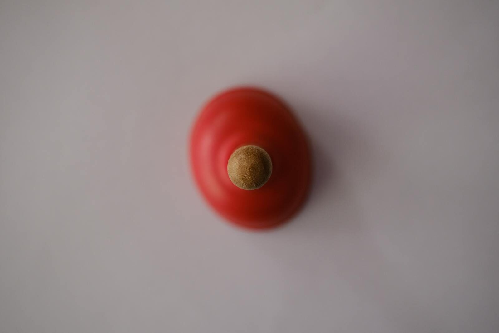 Minimalist top view shot of a red toilet plunger isolated on a white background.