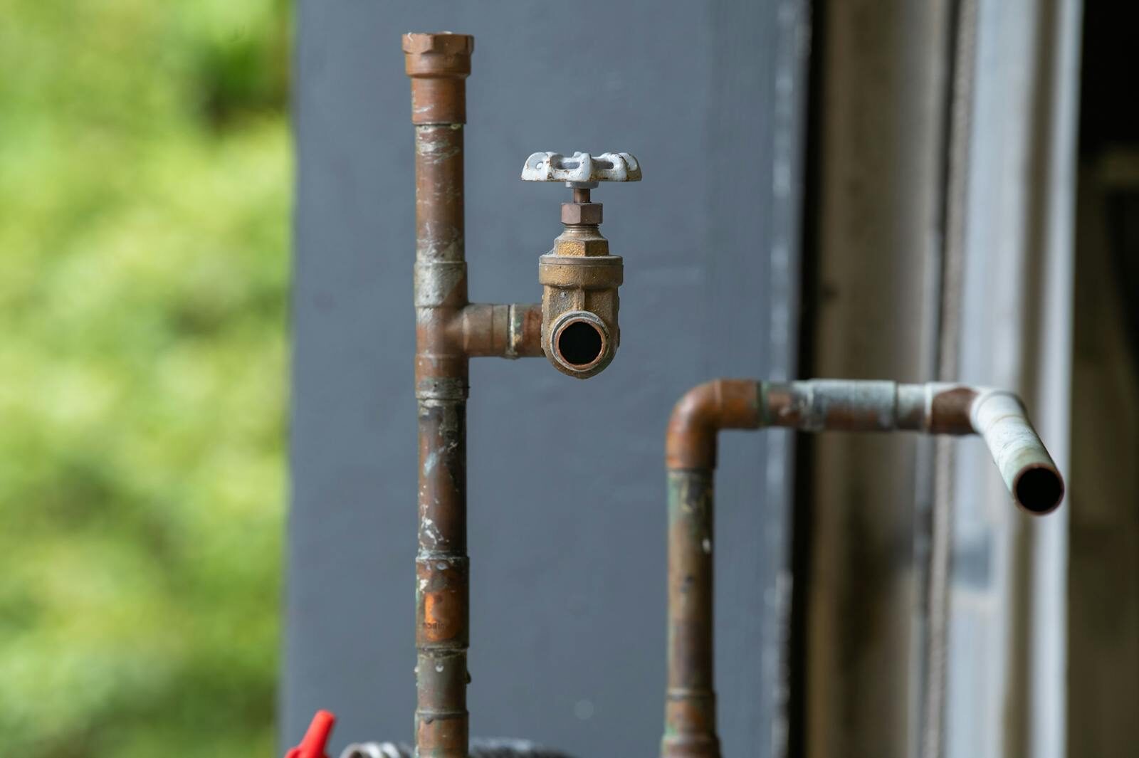 Detailed view of an old, rusty industrial water pipe with valve, conveying vintage industrial aesthetics.