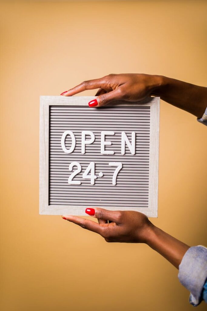 Close-up of hands holding a letter board with Open 24-7 message on a warm background.