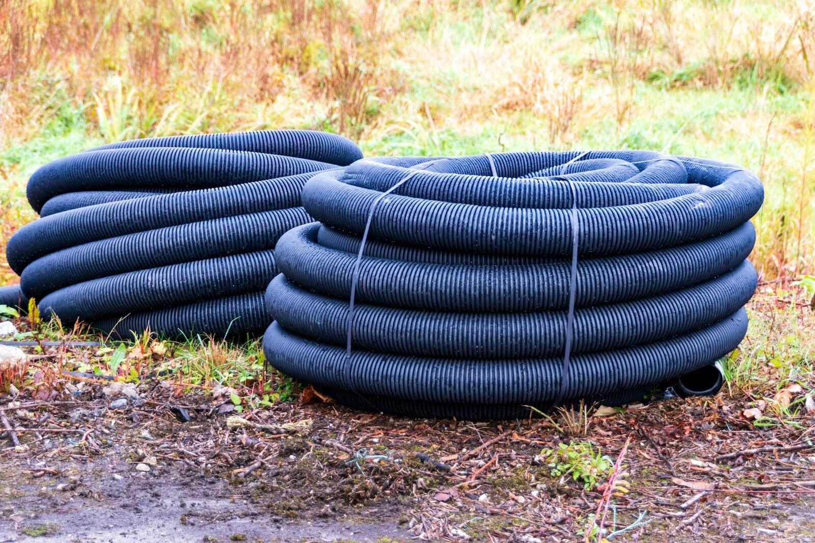 Two coiled black drainage pipes on the ground.