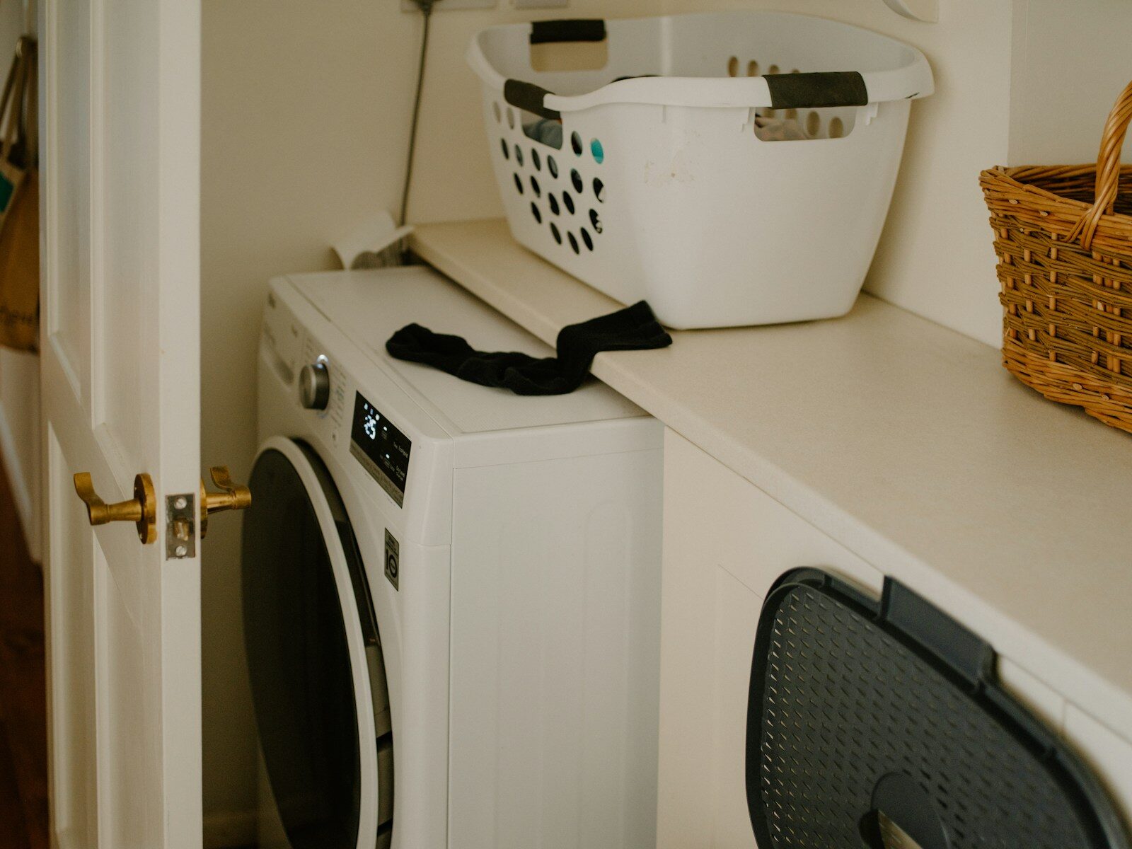 White washing machine with laundry basket and sock.