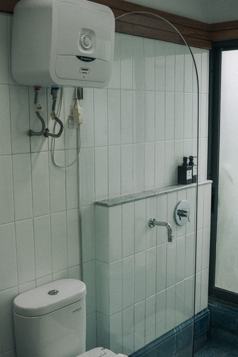 Photo by Asep Rendi a white toilet sitting next to a walk in shower