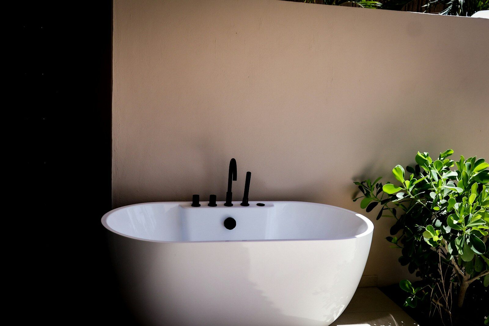 A freestanding bathtub with black fixtures outdoors.
