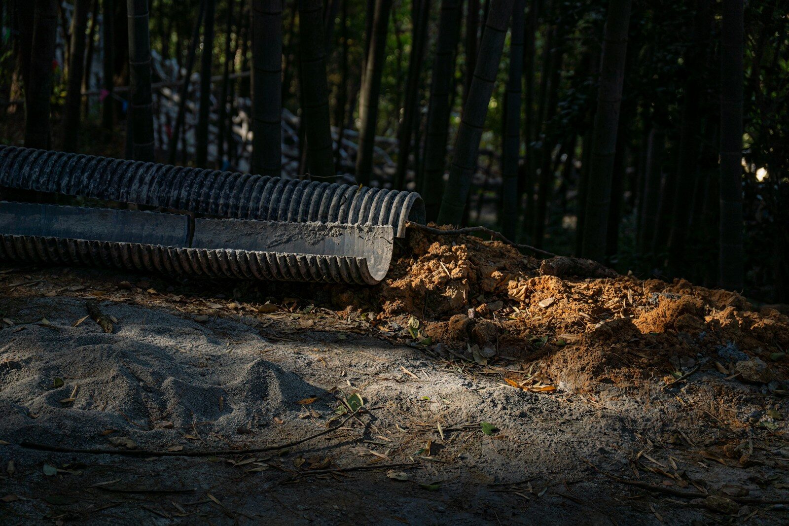 A drainage pipe empties dirt onto a path