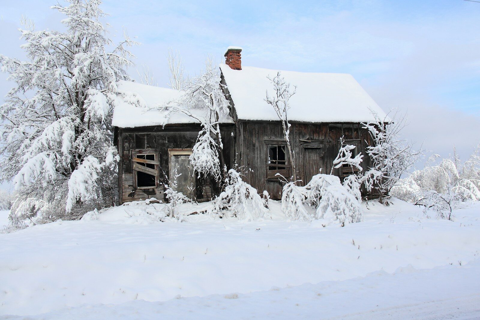 an old run down house with snow on the roof