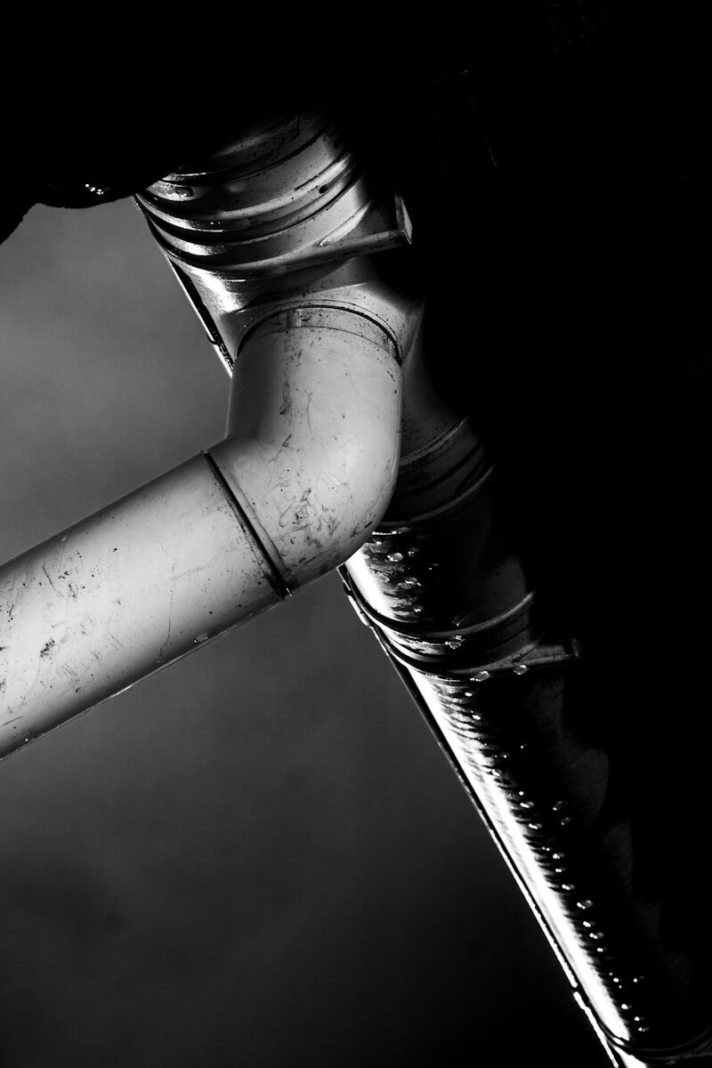 Photo by Juan Pablo Industrial pipes with dramatic lighting in black and white.