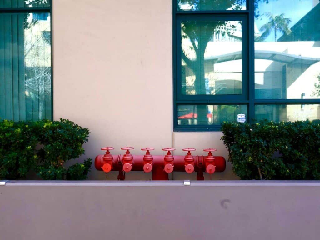 Red fire hydrants lined up on a wall.