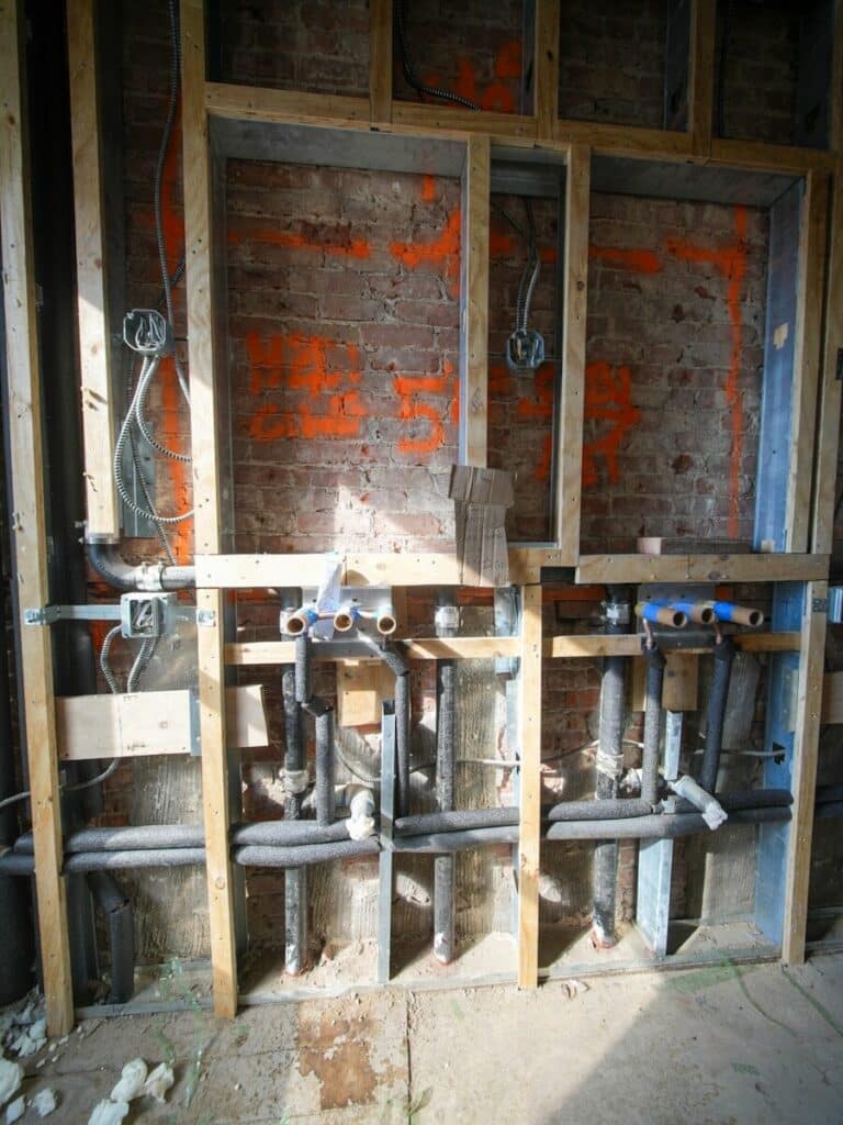 Plumbing and electrical work inside a wall under construction.