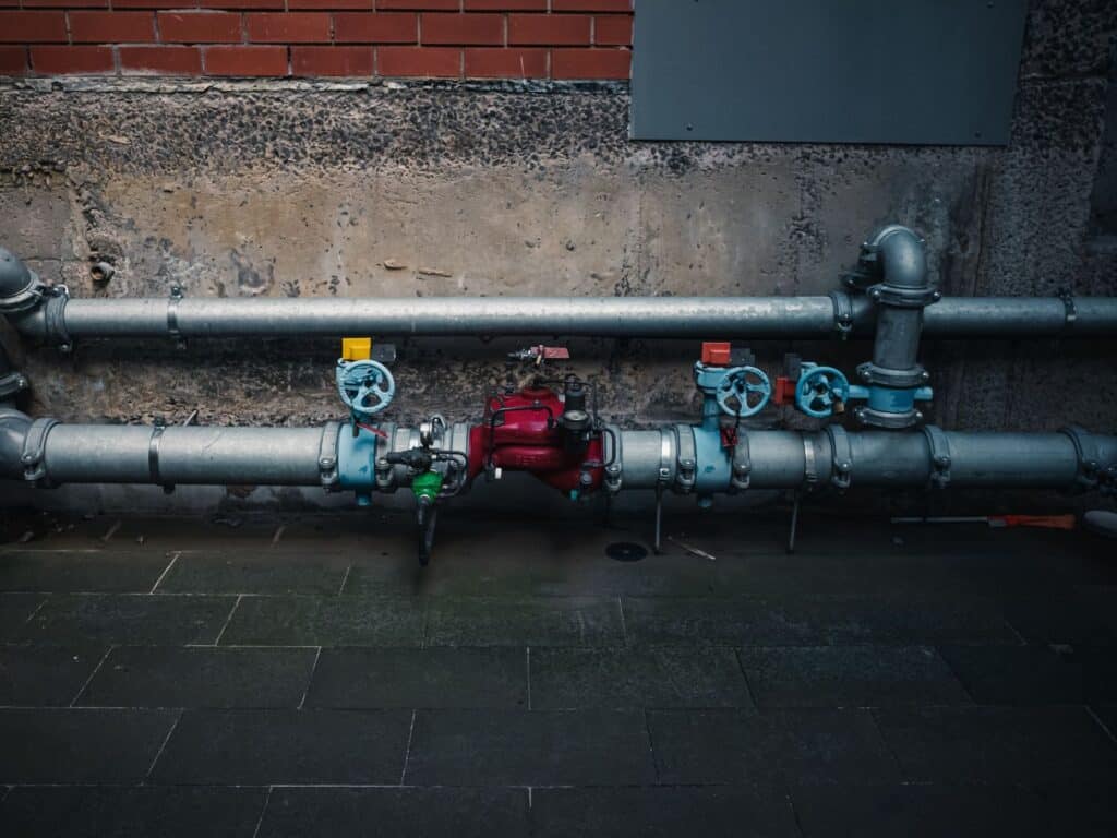 A detailed view of industrial pipes with colorful valves on a textured wall.