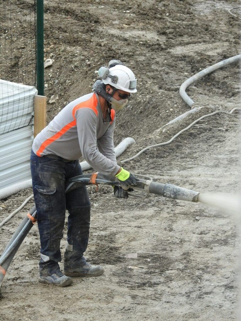 a man in a hard hat and safety gear working on a pipe